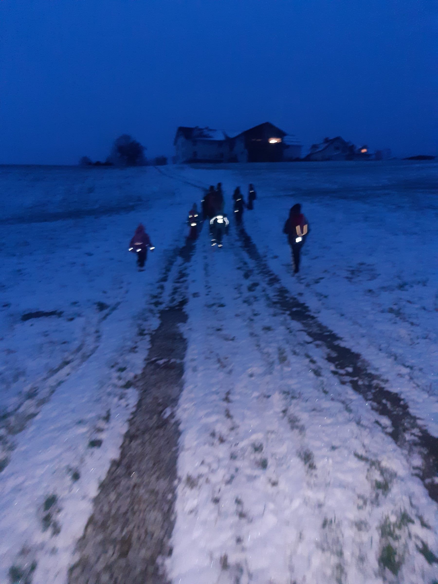 Mit Laternen durch den Schnee in der Abenddämmerung